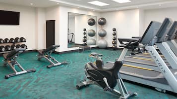Un gimnasio con cintas de correr, elípticas y pesas sueltas.