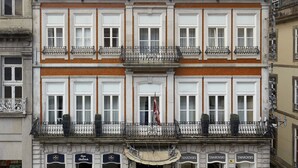 A historic building with a ground-floor shop, multiple balconies, and a classic architectural style. - Grande Hotel do Porto (Porto)