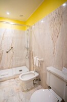 Un baño con ducha, inodoro, bidé y lavamanos.