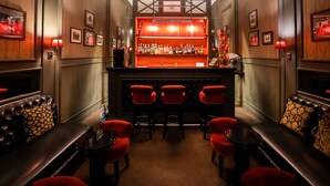 A bar area with a wooden bar counter, multiple stools, and framed pictures on the walls. - Grande Hotel do Porto (Porto)