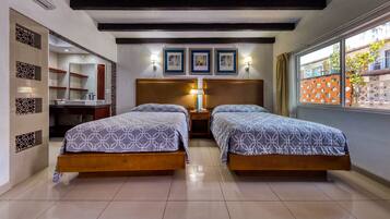 Habitación de hotel con dos camas, baño y ventana con vistas.