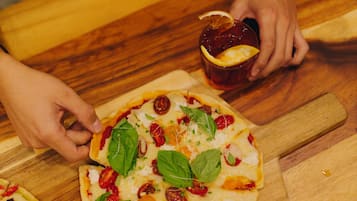 A person placing a pizza on a wooden cutting board.