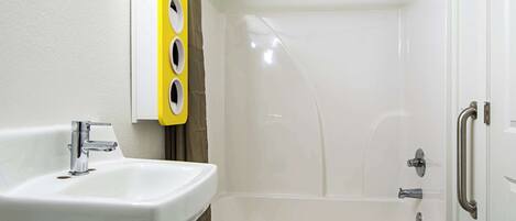 Un baño con un lavabo blanco, una ducha con puerta de cristal y un perchero amarillo.
