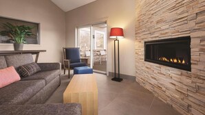 A modern living room with a stone accent wall, a fireplace, a sofa, a coffee table, and a floor lamp. - Country Inn & Suites by Radisson, Northfield, MN (Northfield)
