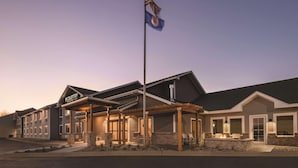 A hotel with a covered outdoor seating area, a flagpole with an American flag, and a sign indicating it is a Country Inn & Suites. - Country Inn & Suites by Radisson, Northfield, MN (Northfield)