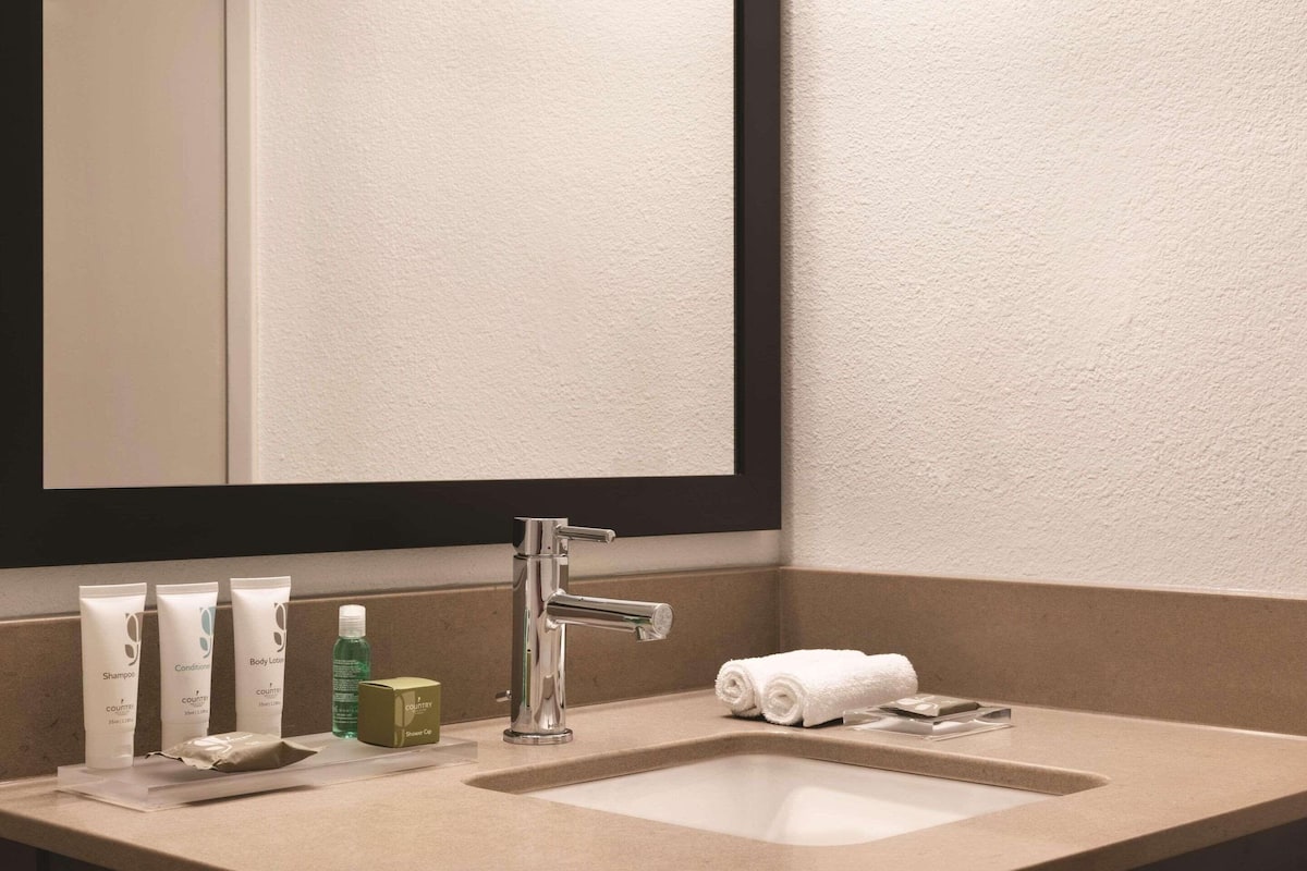 Un baño con lavabo, espejo y artículos de aseo.