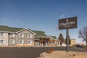 A Country Inn & Suites building with a signboard, parking lot, and a flag.