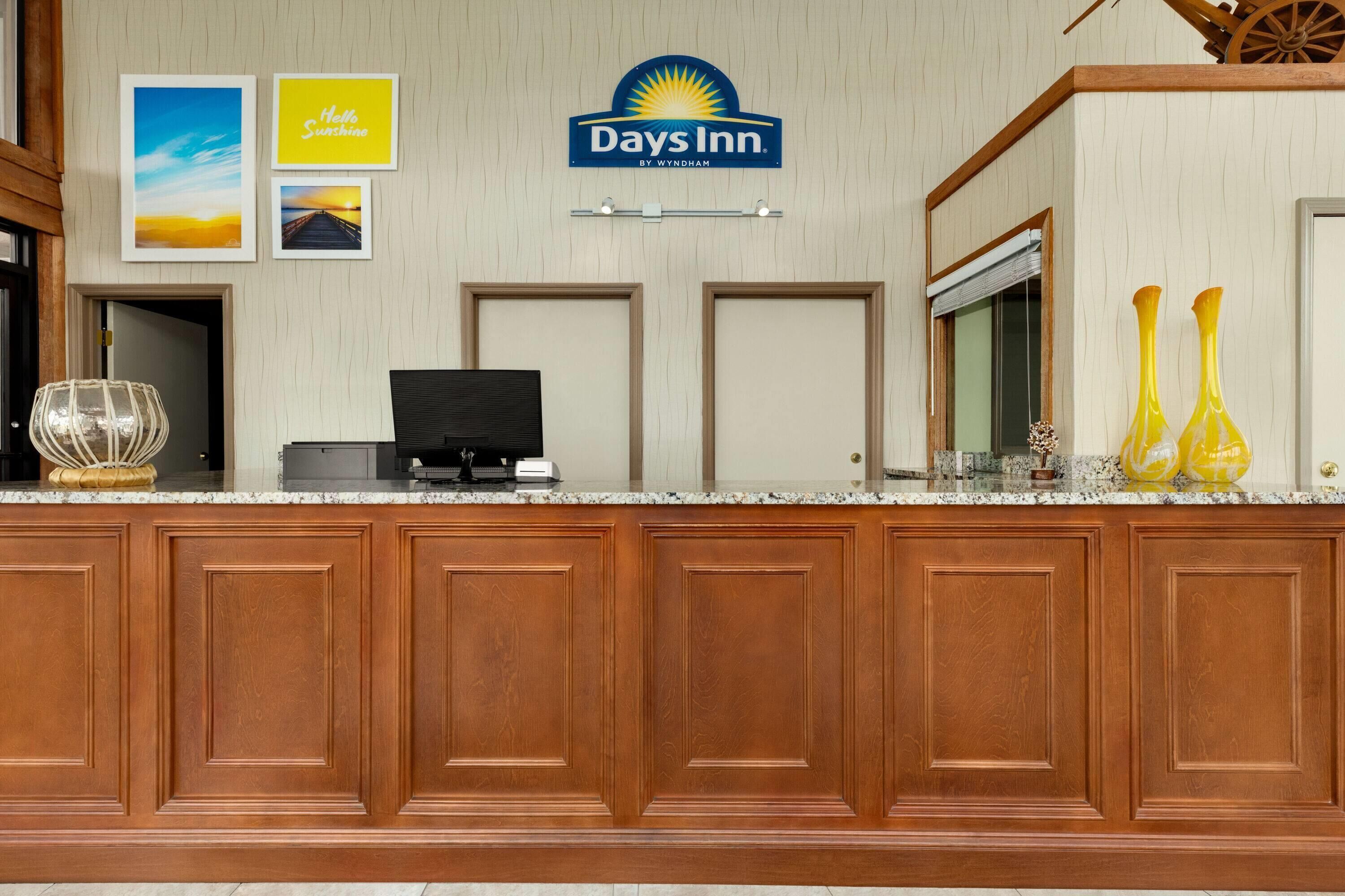 A reception desk with a Days Inn sign, framed pictures, and a wooden panel wall.
