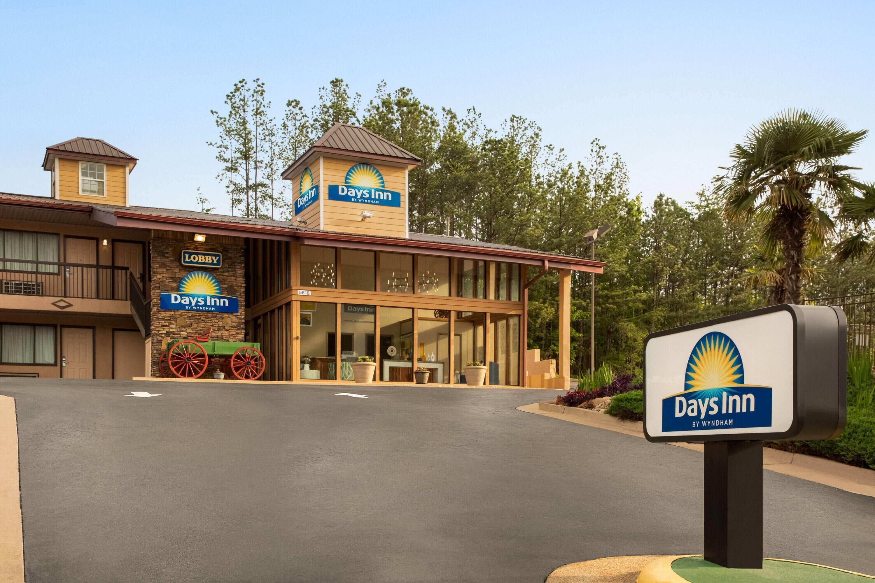 Un hôtel Days Inn avec un panneau d’entrée, une grande entrée vitrée et un parking.