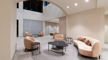 A spacious lobby with a high ceiling, modern seating arrangements, and a view of the night sky through a large window.