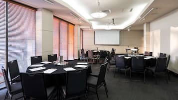 A conference room with a large screen, multiple tables, and chairs.