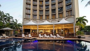 A hotel with a pool, lounge chairs, and a bar area.