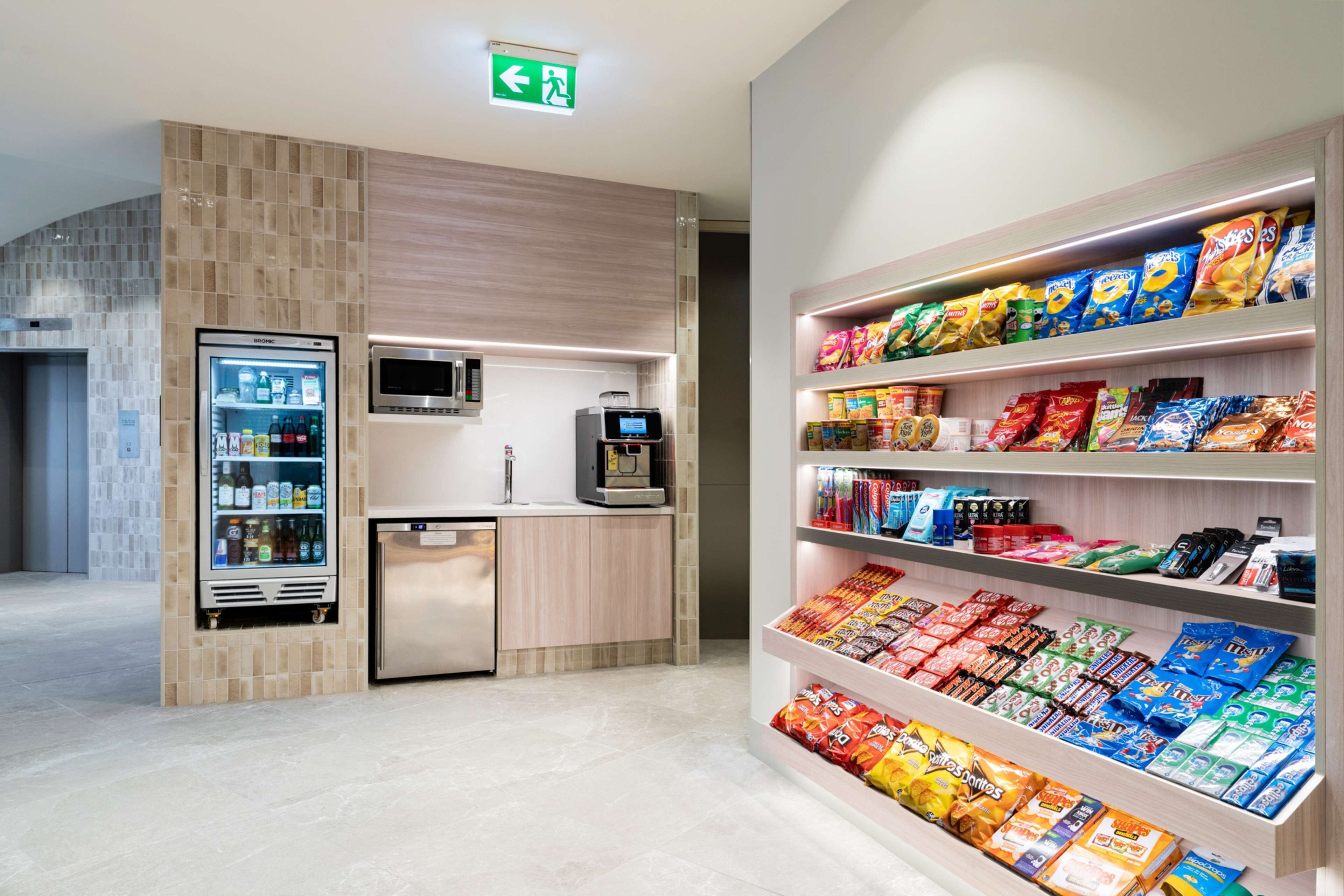 A modern kitchenette with a refrigerator, microwave, and coffee machine.