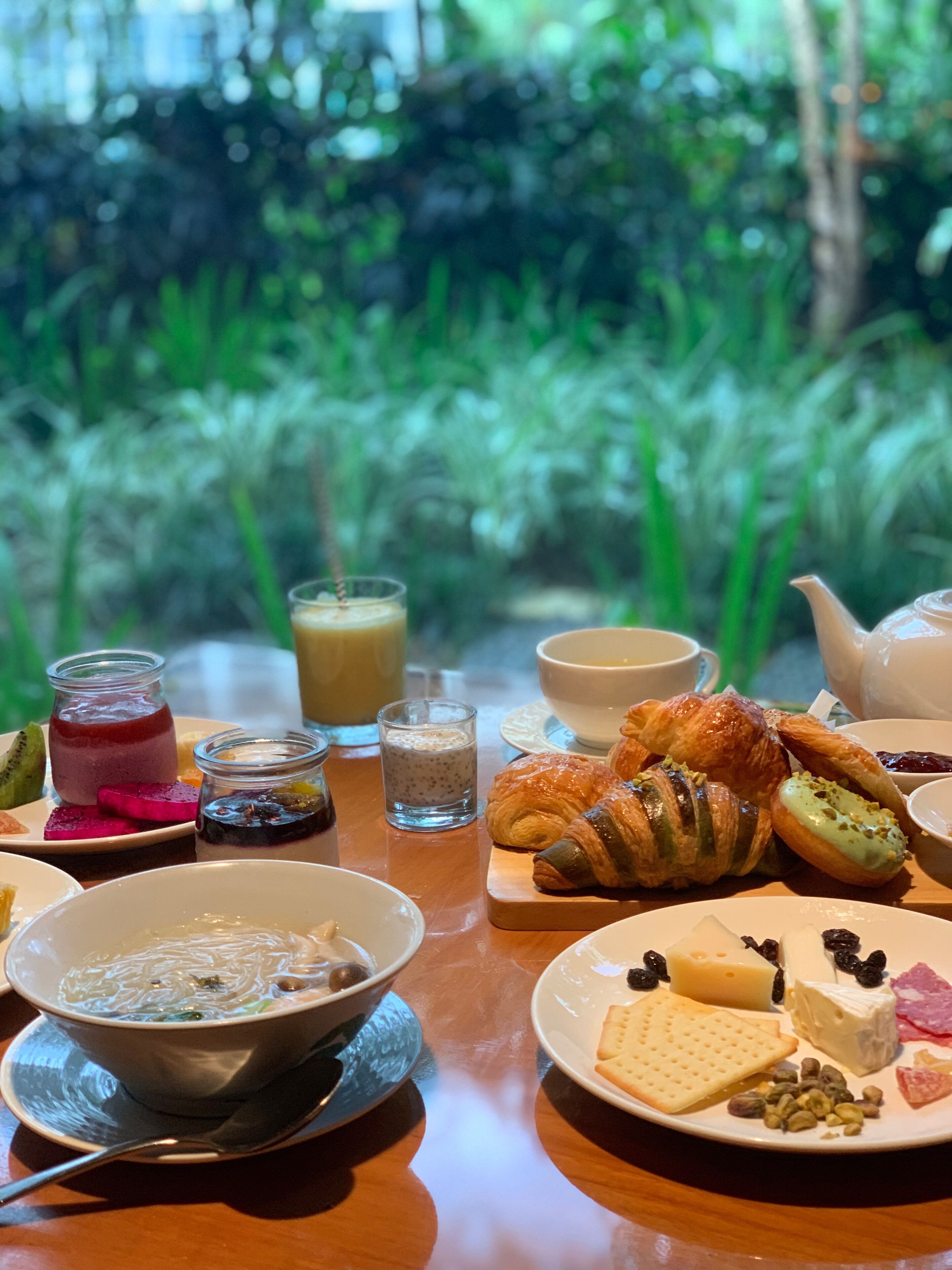 A table set with various food items including pastries, cheese, and a bowl of soup.