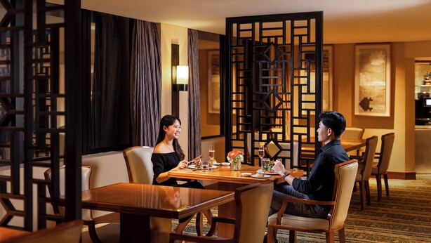 Un comedor con mesa de madera, sillas y un separador decorativo.