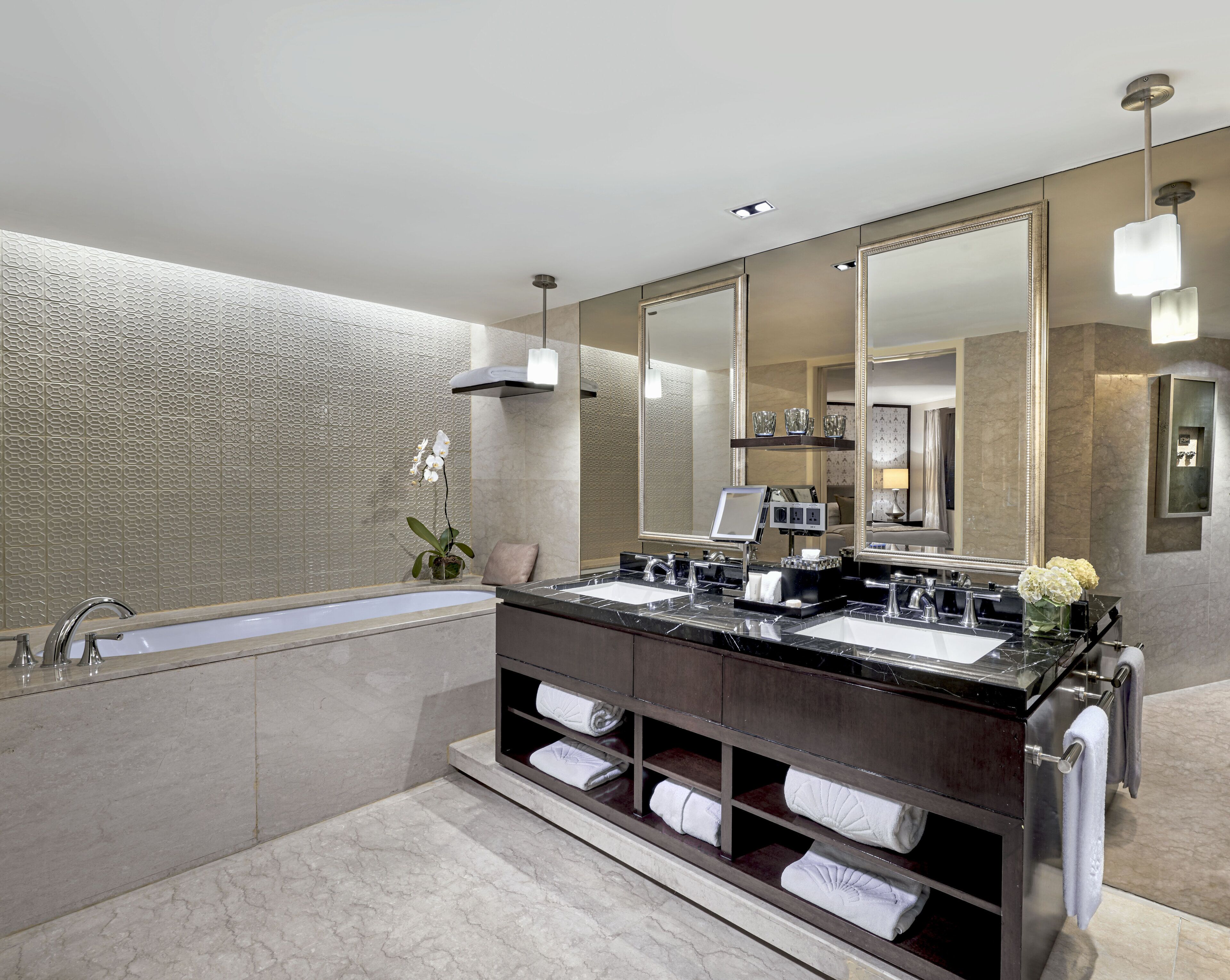 A modern bathroom with a double sink vanity, a large mirror, and a bathtub.