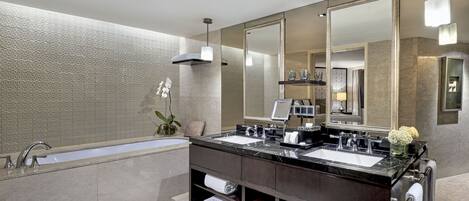 A modern bathroom with a double sink vanity, a large mirror, and a bathtub.