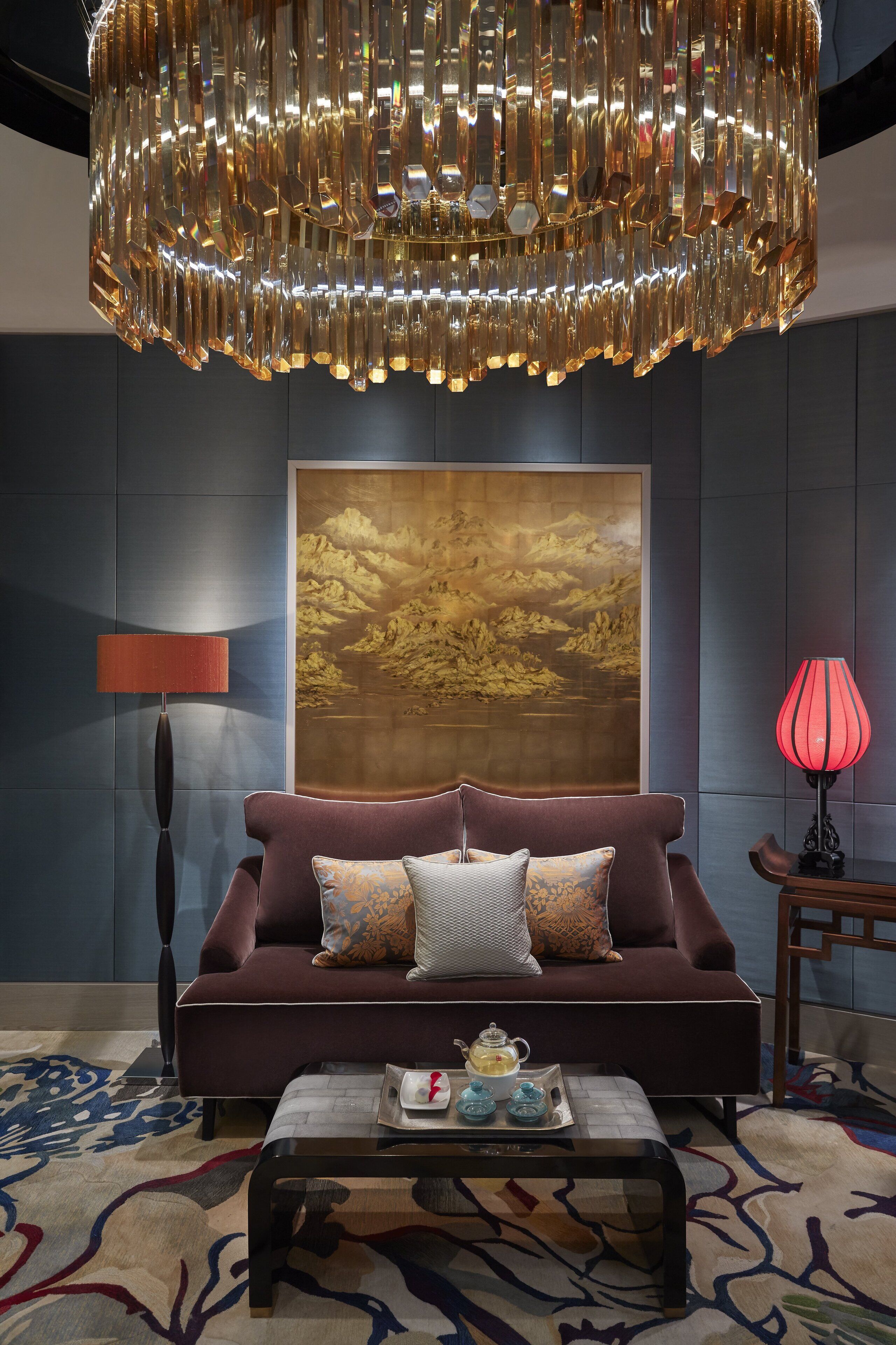 A modern living room with a large sofa, a coffee table, and a chandelier.