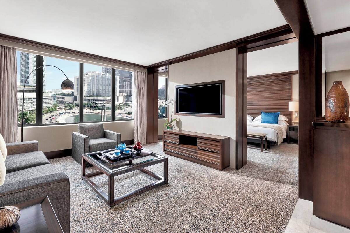 Una habitación de hotel moderna con vista a la ciudad, televisor de pantalla plana, sofá, mesa de centro y cama con mesita de noche.