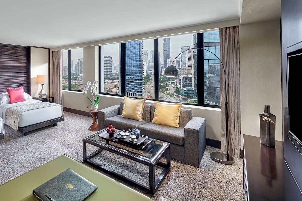 Habitación de hotel con dos camas, un sofá, una mesa de centro y un televisor.