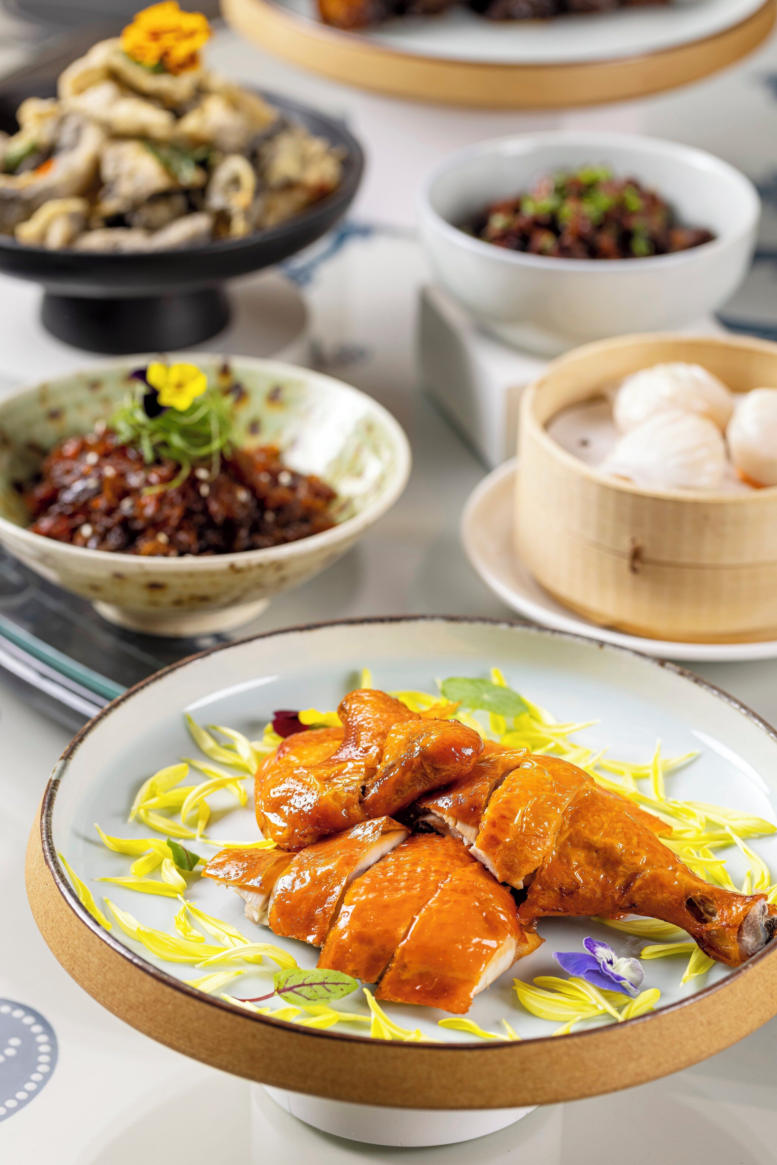 A table with various dishes, including a plate of roasted chicken and several bowls of different foods.
