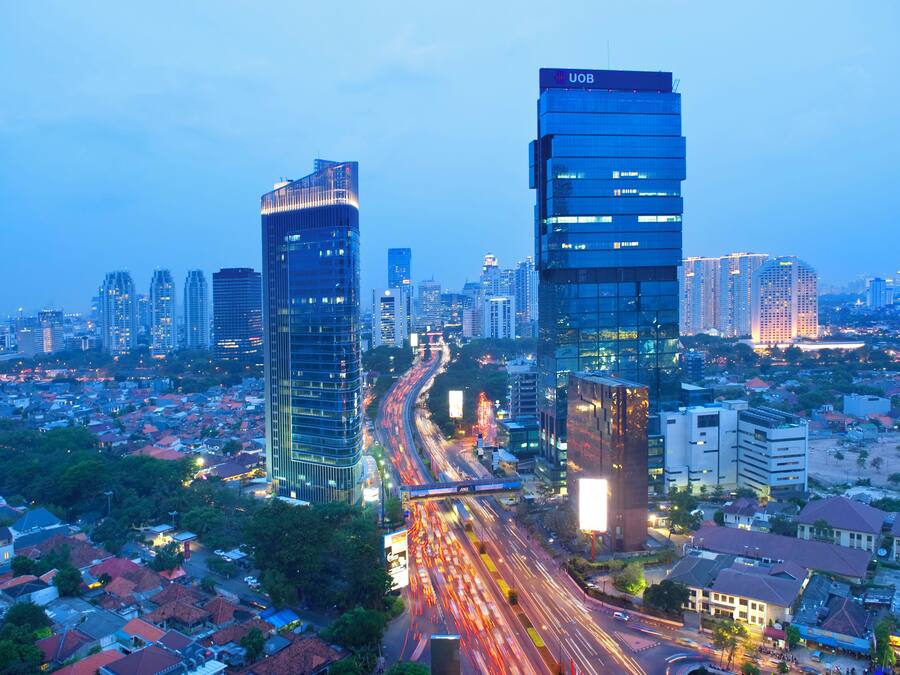 Un paysage urbain avec des immeubles modernes de grande hauteur, une autoroute très fréquentée et des quartiers résidentiels.