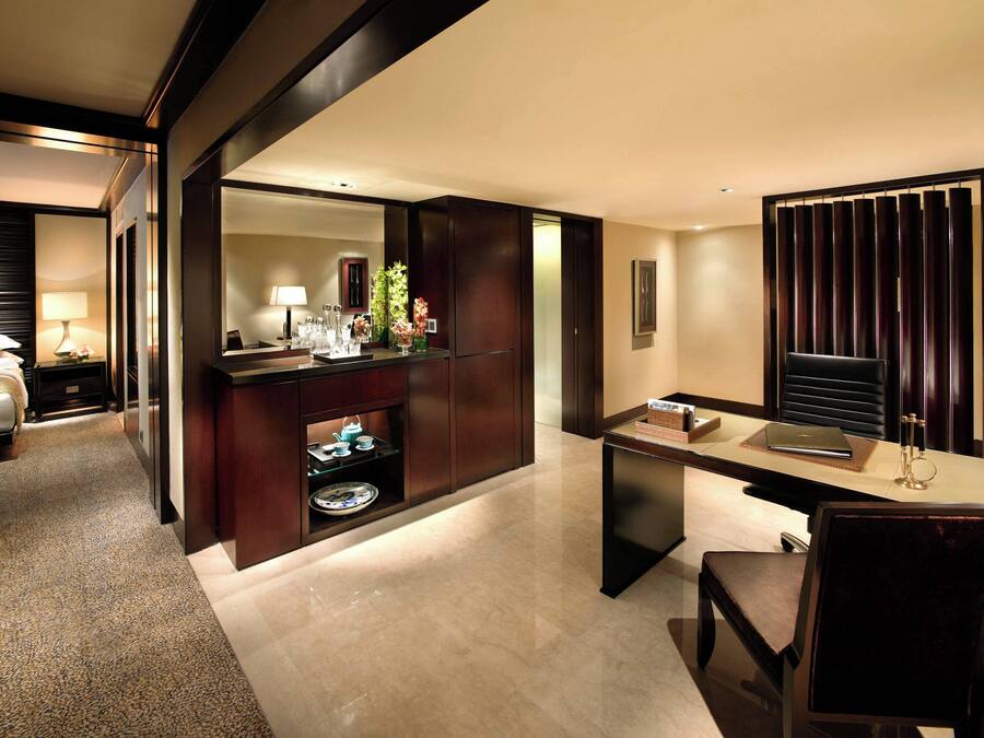 A hotel room with a bed, a desk, a chair, a mirror, a dresser, and a bathroom.