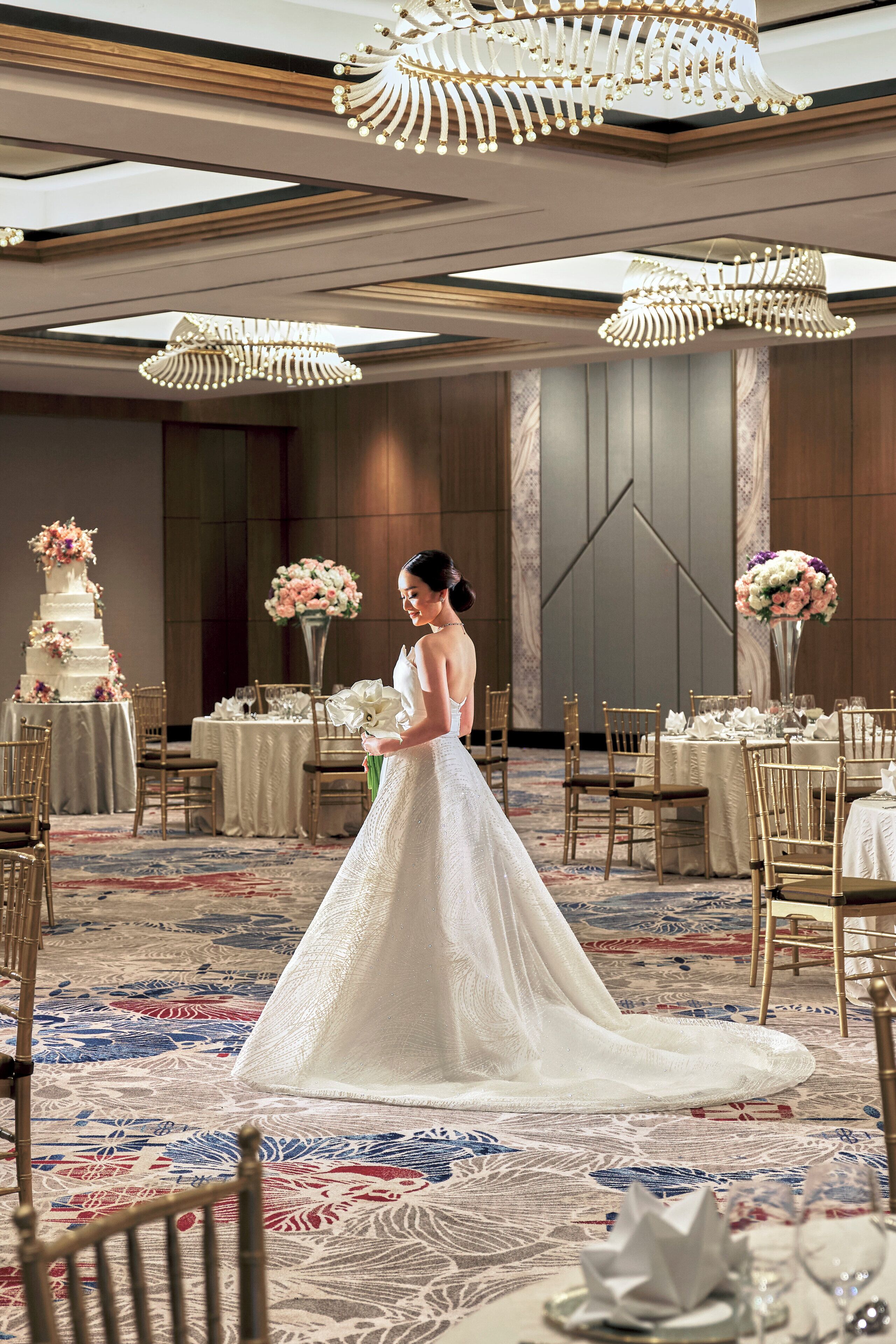 A wedding venue with a bride in a white gown, tables set for a reception, and a multi-tiered wedding cake.