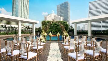 Decoração de casamento ao ar livre com piscina, flores e vista para prédios da cidade.