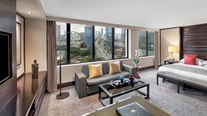 Una habitación de hotel moderna con una cama grande, un sofá, una mesa de centro y una televisión.