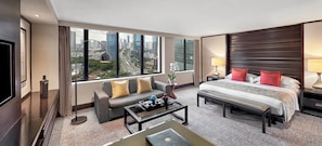 A modern hotel room with a large bed, a sofa, a coffee table, and a TV. - Mandarin Oriental, Jakarta (Jakarta)
