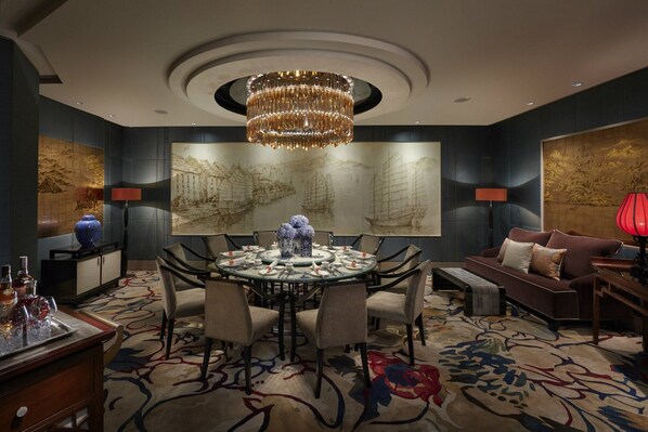 A formal dining room with a round table, chairs, and a chandelier.