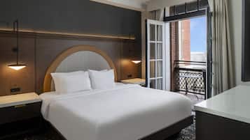 A hotel room with a large bed, two bedside tables, a headboard with a circular design, a small table, and a view of the outside.