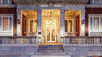 A grand entrance with a central staircase leading to a double door, flanked by columns and a balustrade.