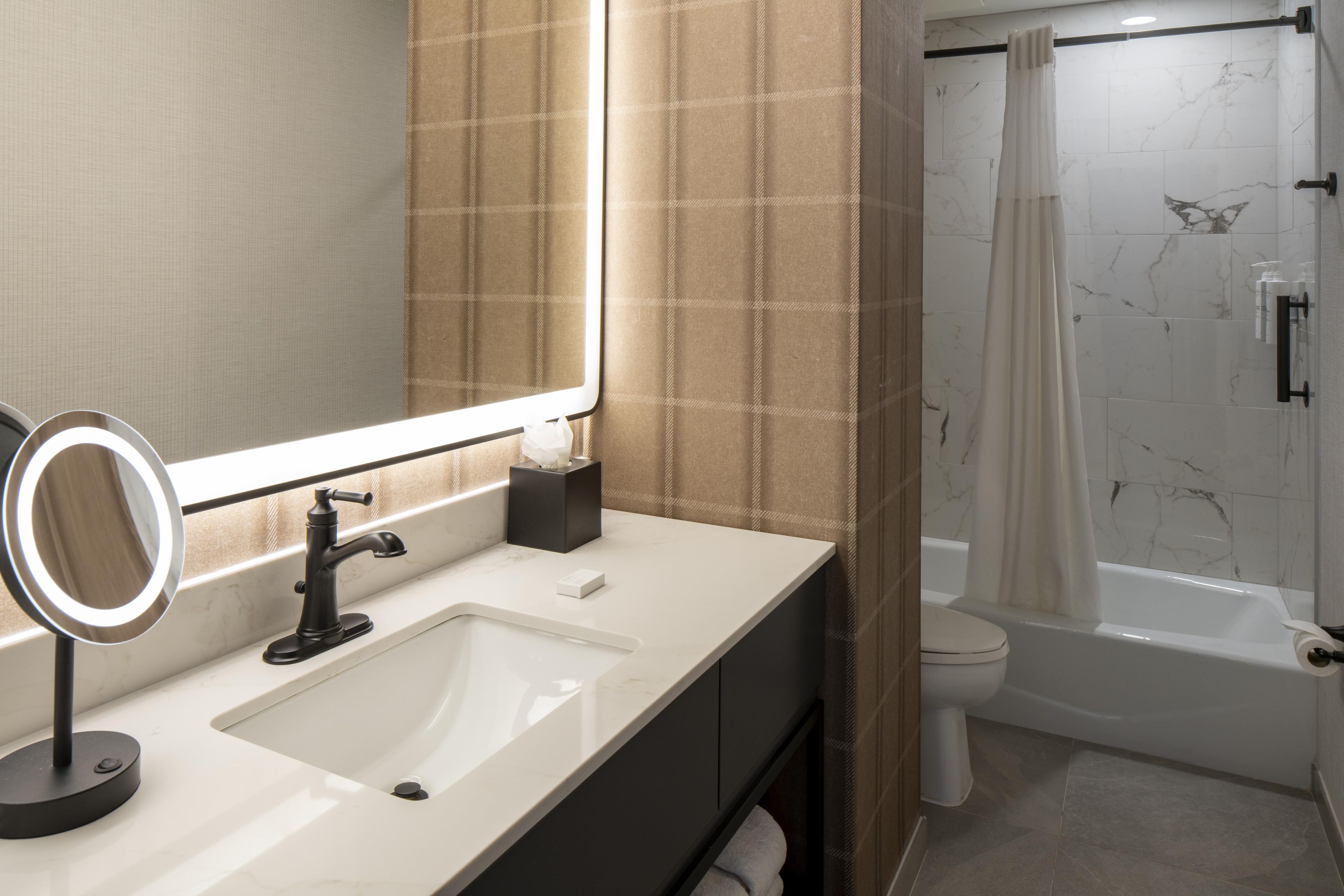 A bathroom with a sink, mirror, and a shower area.