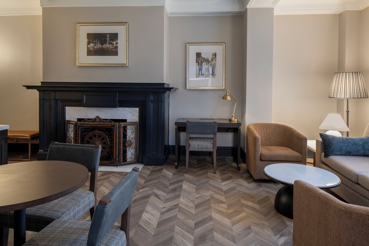 A room with a fireplace, a dining table, a sofa, and a lamp.