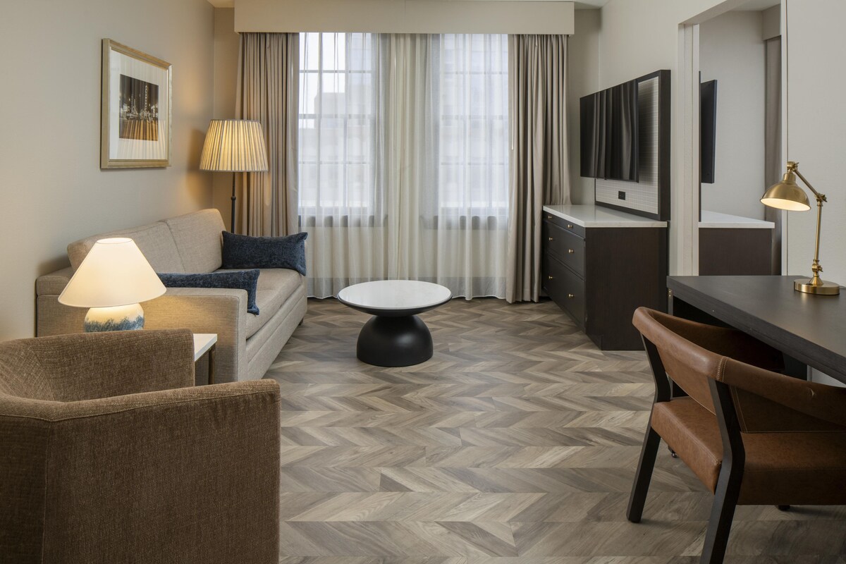 Une chambre d’hôtel avec un canapé, une table à manger, un téléviseur et une lampe.