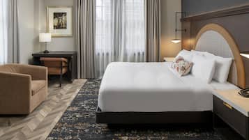 A hotel room with a bed, a desk, a chair, and a large window with curtains.