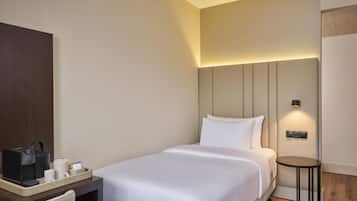 Una habitación de hotel con cama, mesita de noche y una pequeña mesa con lámpara.