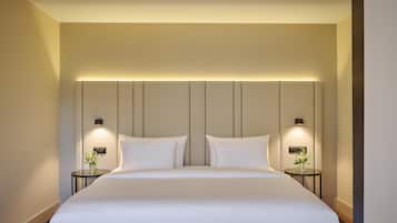 A modern hotel room with a large bed, two bedside tables with lamps, and a wall-mounted light fixture above the bed.
