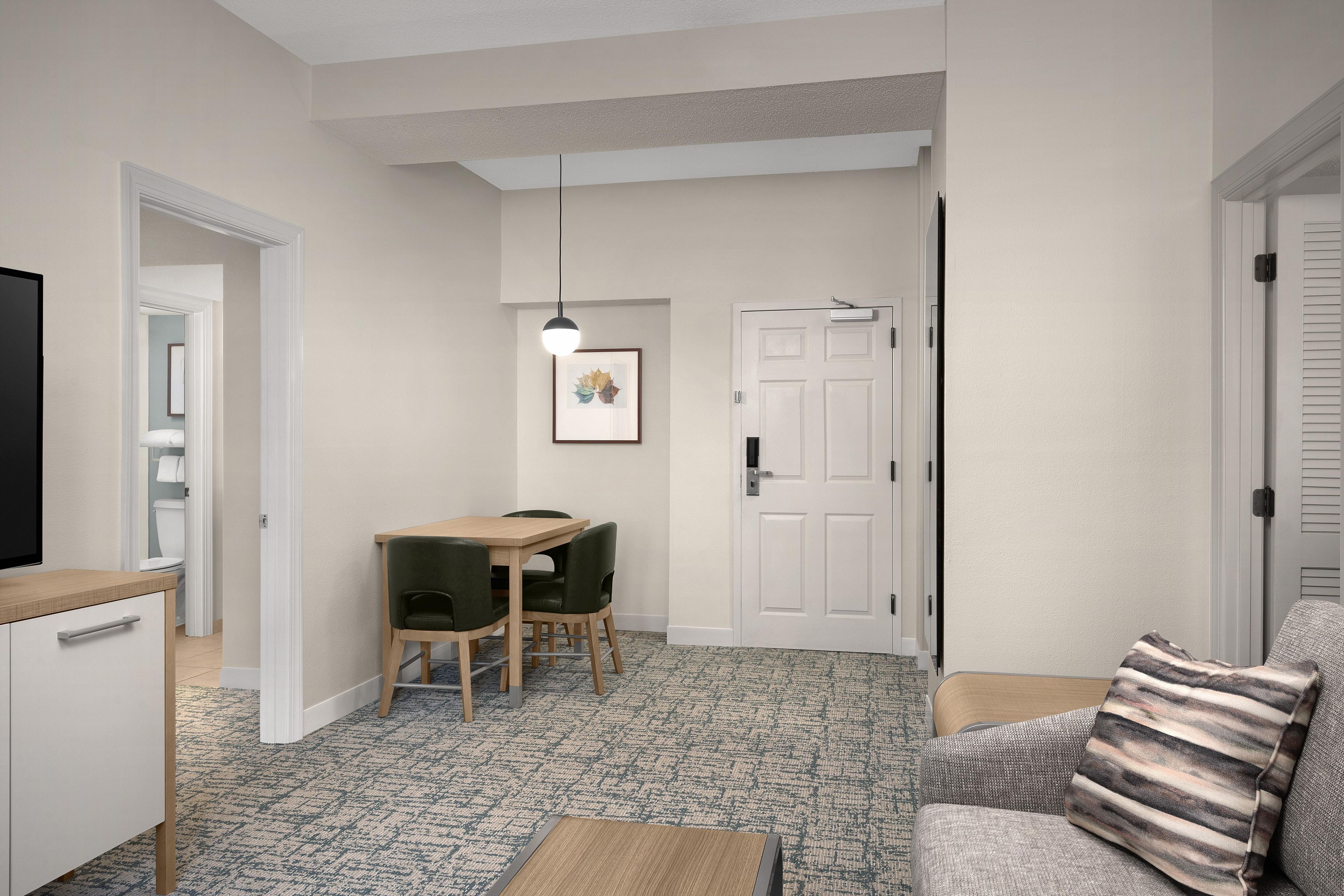 A compact living space with a kitchenette, a dining area with a table and chairs, a sofa, and a television.