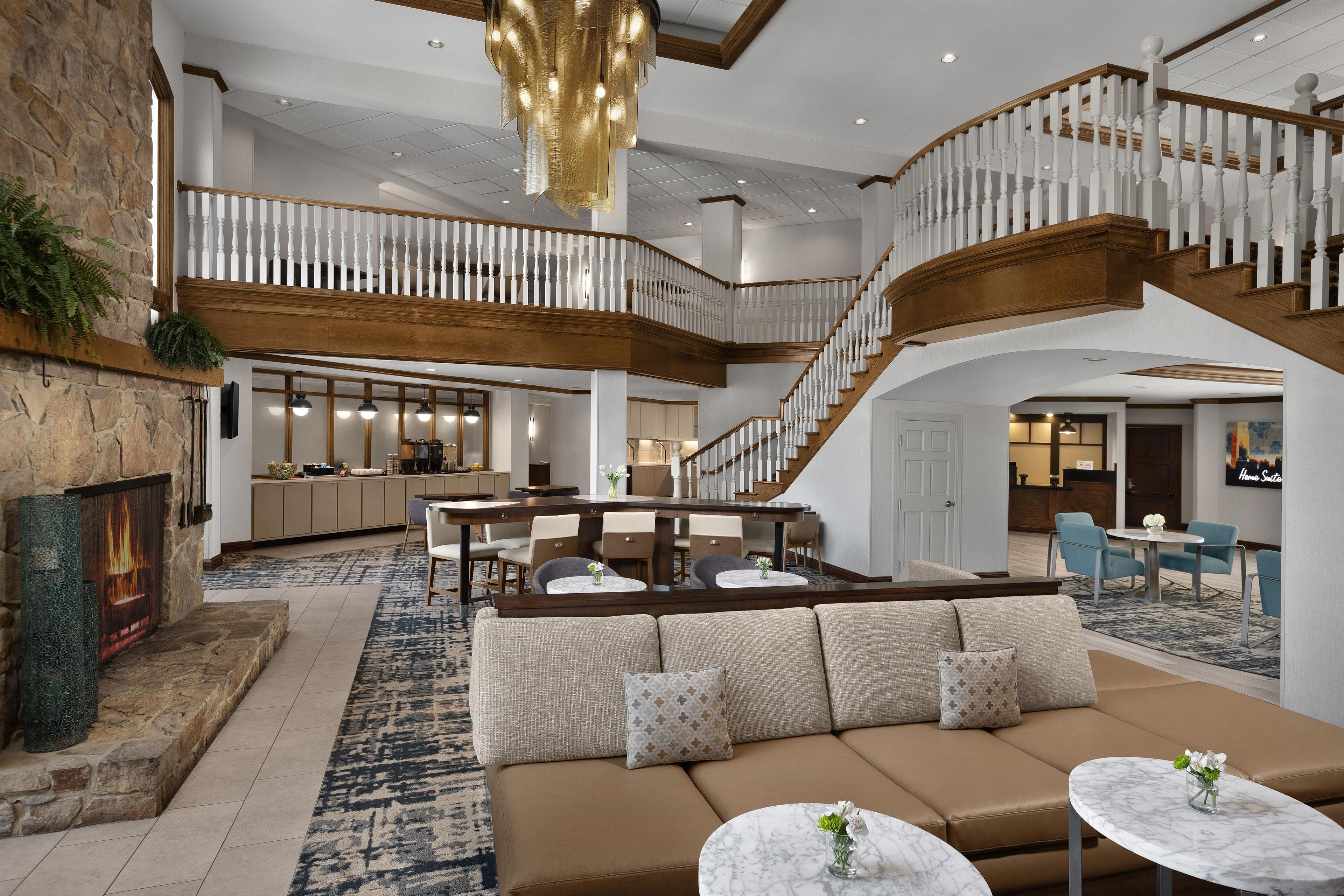 A spacious lobby with a high ceiling, a grand staircase, and a seating area with a fireplace.