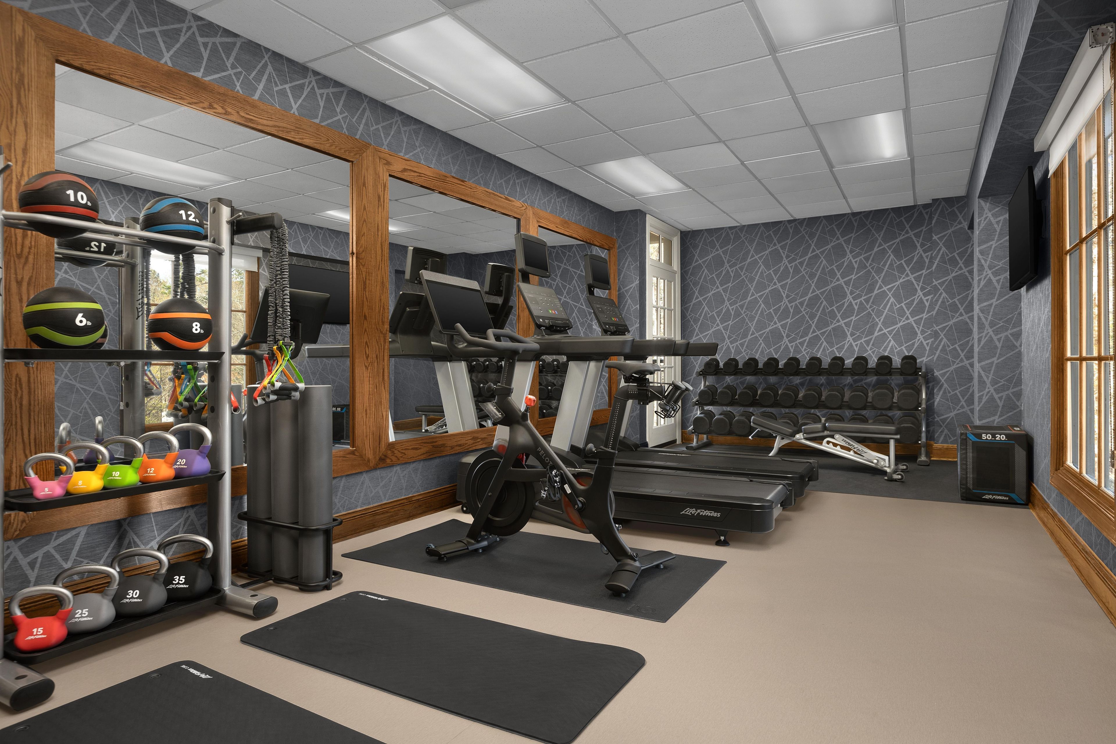 Un gimnasio con equipo de ejercicio, pesas y un espejo.