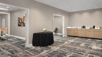 A conference room with a carpeted floor, a table with a black tablecloth, and a painting on the wall.
