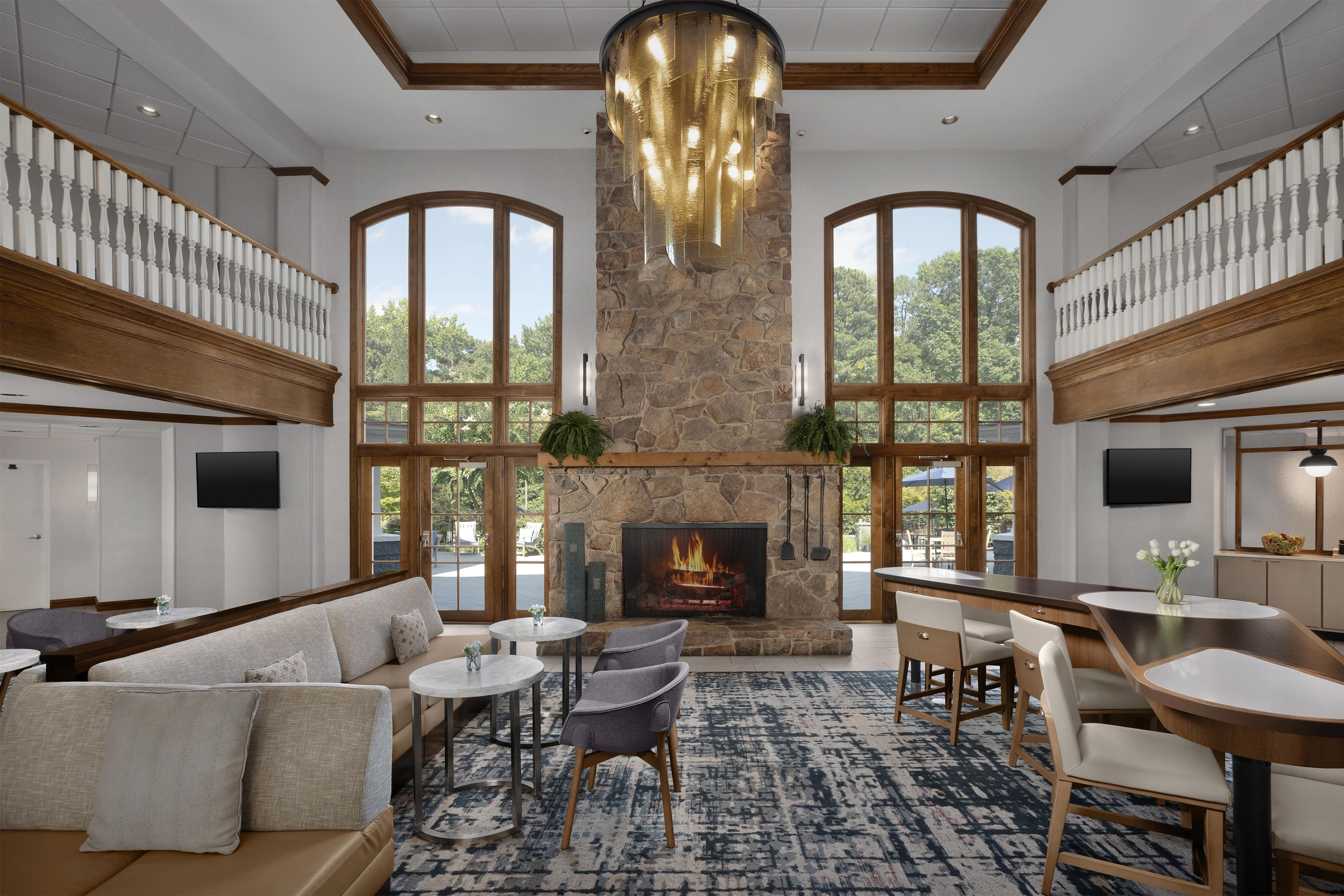 A spacious lounge area with a stone fireplace, comfortable seating, and large windows offering a view of the outdoors.