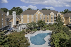 A hotel with a swimming pool, outdoor seating, and a covered patio area. - Homewood Suites by Hilton Raleigh/Cary (Cary)
