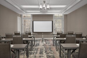 A conference room with a large projection screen, multiple tables, and chairs arranged for meetings. - Homewood Suites by Hilton Raleigh/Cary (Cary)
