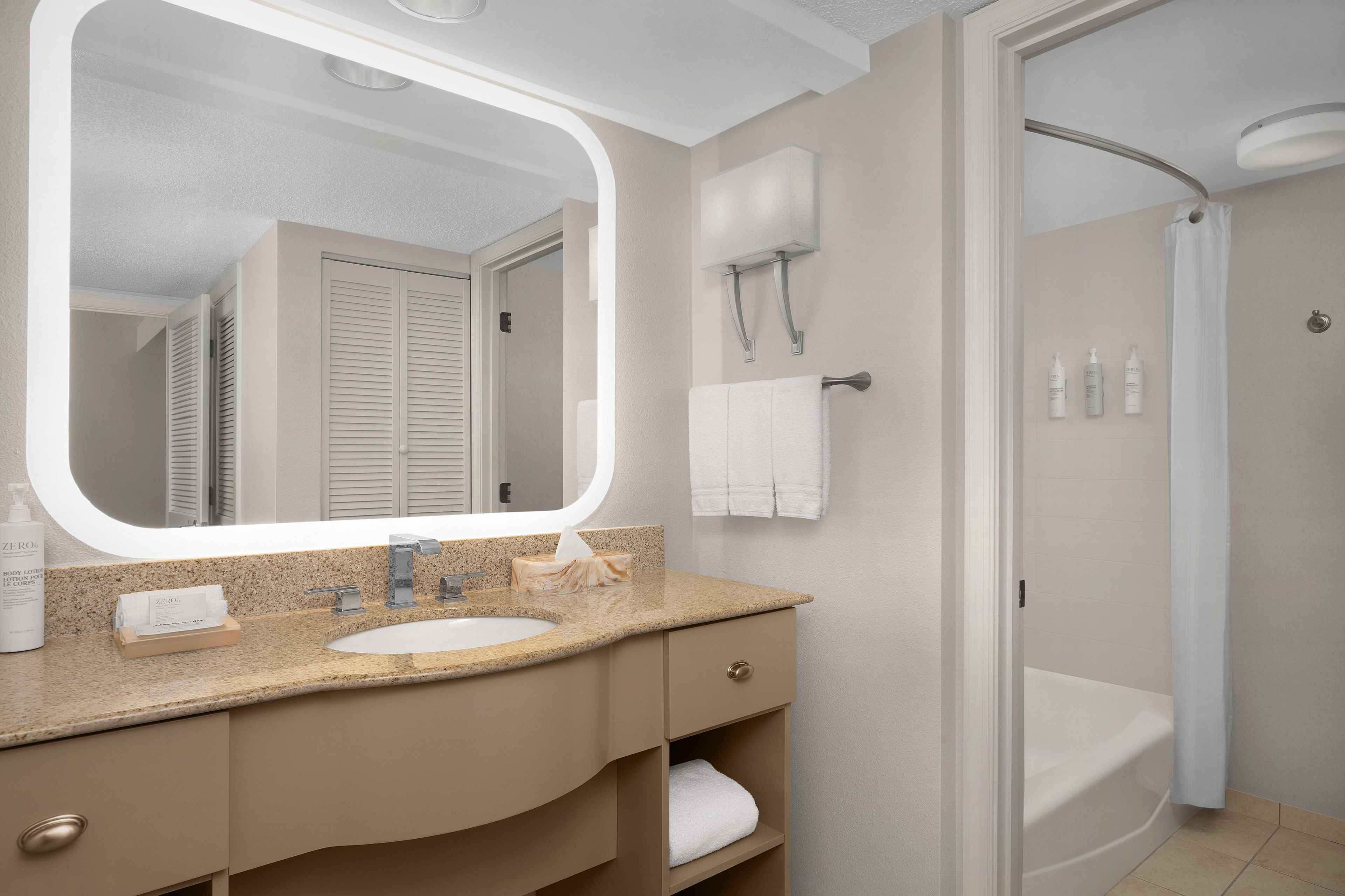 A bathroom with a sink, mirror, towel rack, and shower.