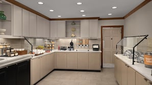 A modern kitchen with built-in appliances, a coffee station, and a door leading to another room. - Homewood Suites by Hilton Raleigh/Cary (Cary)