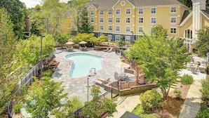 A hotel with a swimming pool, outdoor seating, and a garden area. - Homewood Suites by Hilton Raleigh/Cary (Cary)
